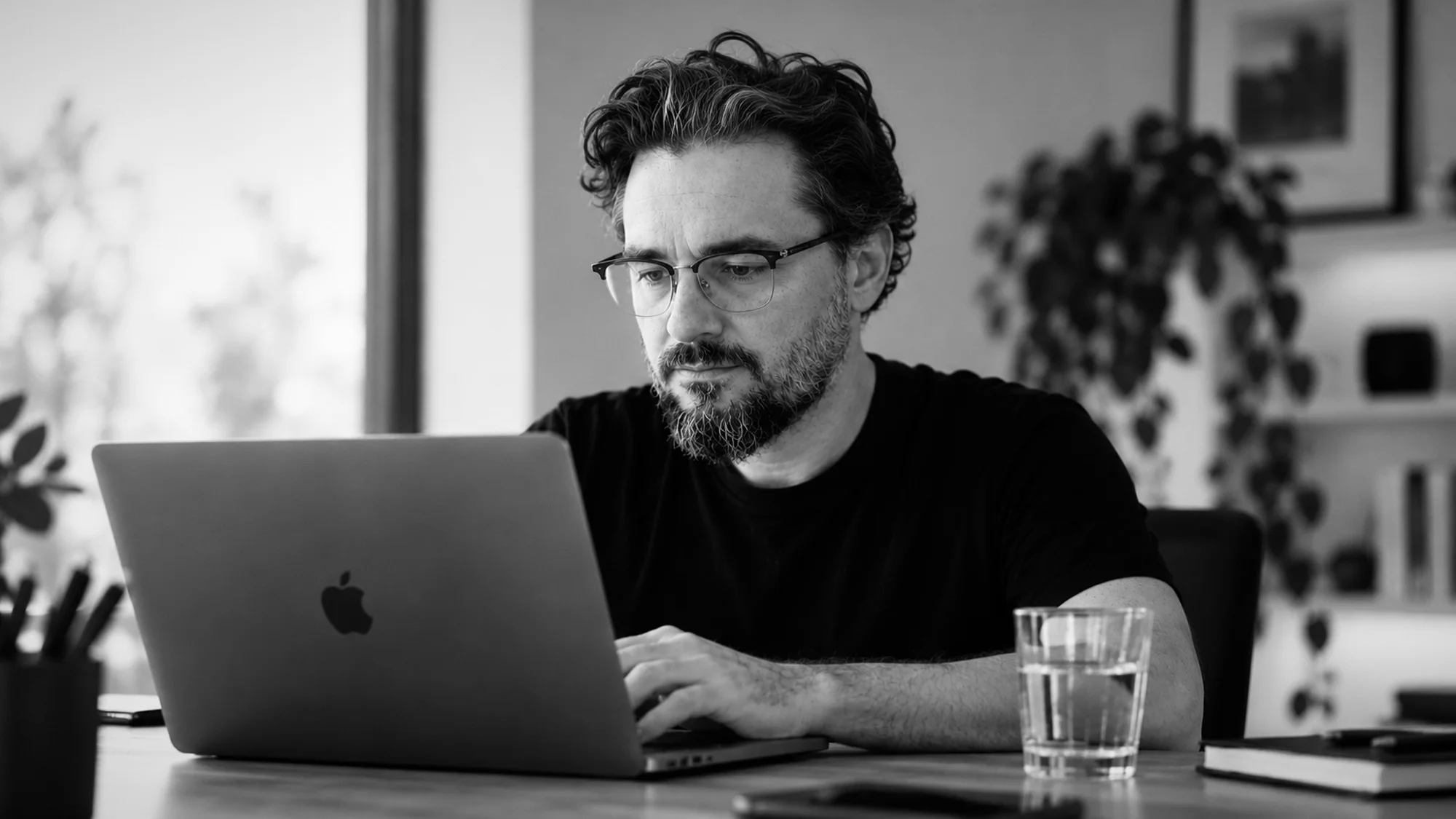 Black-and-white portrait of Stefan Szakal working at a laptop.